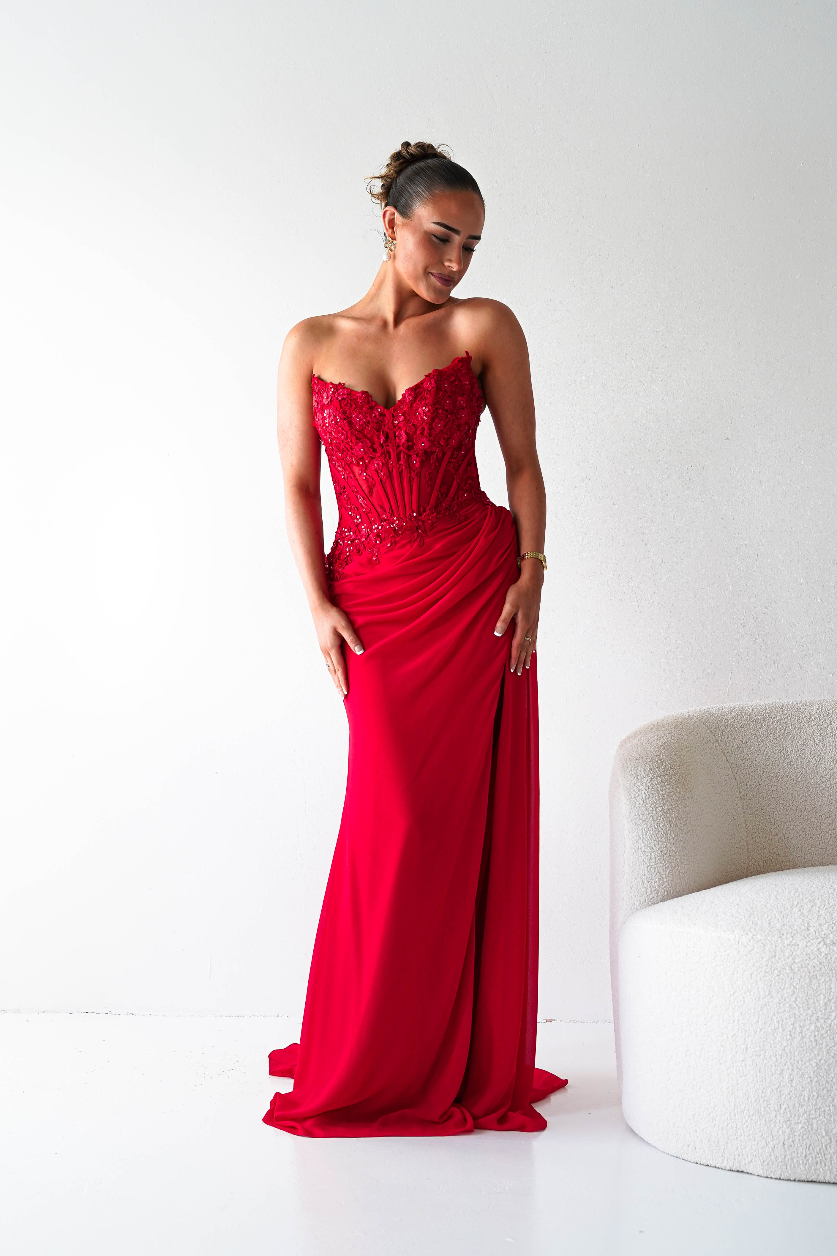 Woman in a red evening gown standing against a white background