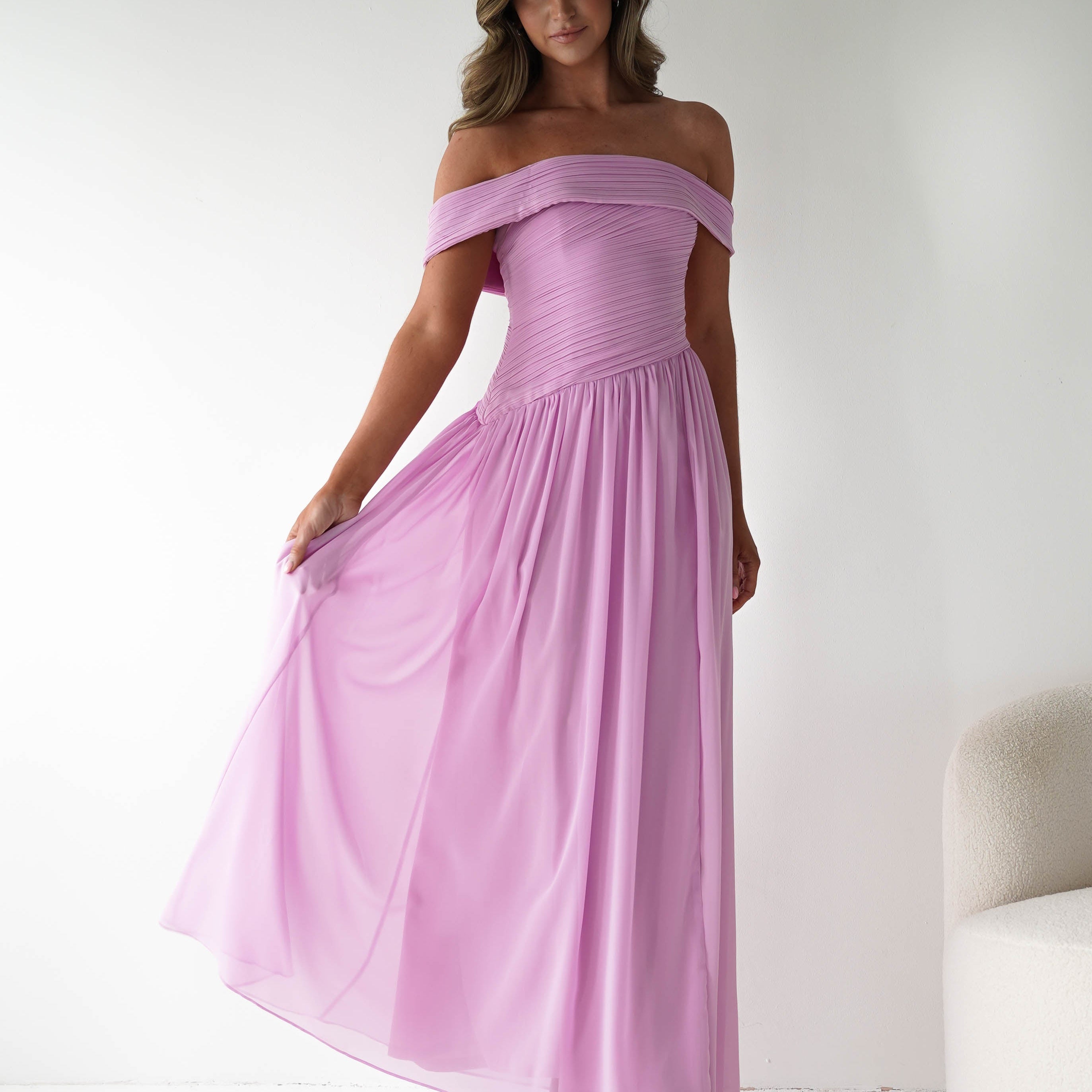 Woman wearing a pink off-shoulder dress against a white background
