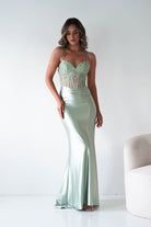 Woman wearing a mint green evening gown with a white background