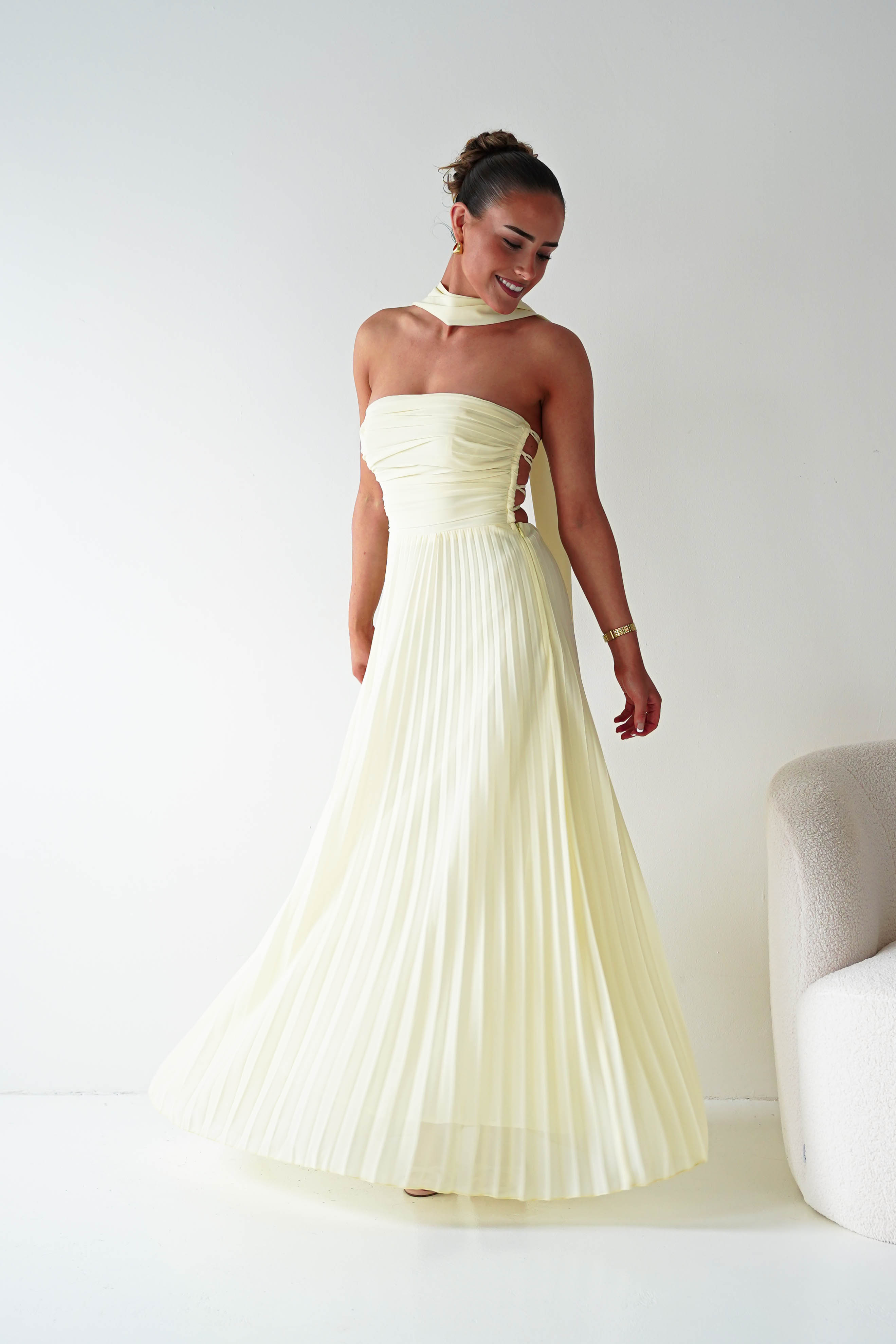 Woman wearing a strapless, light-colored evening gown against a plain background