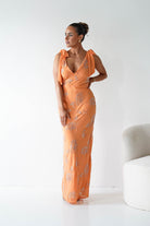 Woman wearing an orange floral dress against a white background